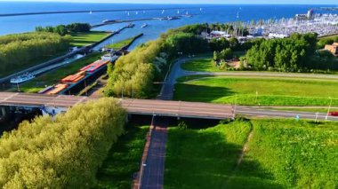 Barajın oradaki köprünün üzerinde konteynırlarla dolu büyük bir mavna duruyor. Hollanda, Lelystad 'ın yeşil rıhtım üzerinde uçuş.