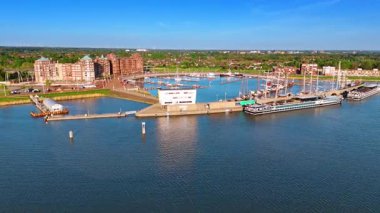 Markermeer Gölü üzerindeki Hollanda 'nın pitoresk Lelystad limanına yaklaşıyoruz. Eski gemiler ve modern yatlar rıhtımlarda duruyor. Hava görünümü.