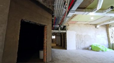 Yenilenmiş binanın uzun koridorunda yürüyorum. Tavanda kablolar ve borular var. Yeniden yapılanma kavramı.