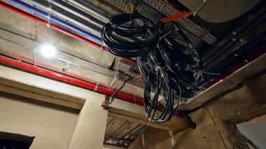 Odanın tavanından sarkan katlanmış siyah kablolar. Binanın aydınlatma ekipmanında düşük açı görüntüsü.