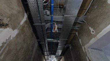 Uzun koridorun tavanındaki borular, kablolar ve metal yapılar. Tadilat yapılan binalara bir göz atın. Düşük açı görünümü.