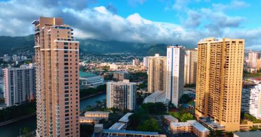 Ala Wai Kanalı yakınlarındaki Waikiki manzarasının üzerinde yükseliyor. Kalın ağır bulutlar arka planda toplanıyor.