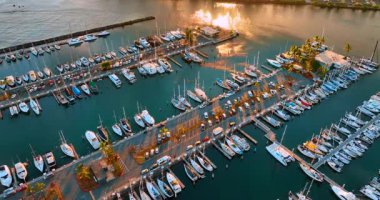 Rıhtımlarında çok sayıda araç bulunan büyük yat kulübünün üstünde uçuş. Batan güneş Pasifik Okyanusu 'nun sularına yansıyor..