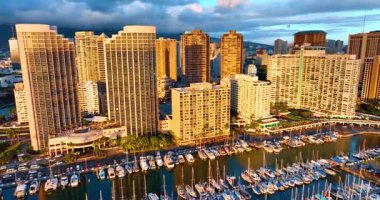 Gün batımının altın ışığında Waikiki 'nin güzel mimarisi. Pasifik Okyanusu 'nun su manzarasında büyük bir yat kulübü. Arka planda dramatik bulutlar. Hava perspektifi.