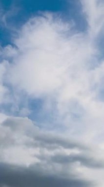 Gökyüzündeki katman bulutlarının zaman akışı. Mavi gökyüzünde akan bulutlar. Dikey video