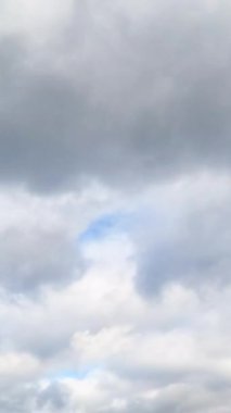 Gökyüzünde kayan hafif yüksek bulutlar. Mavi gökyüzündeki bulutlar hareket ediyor. Dikey video