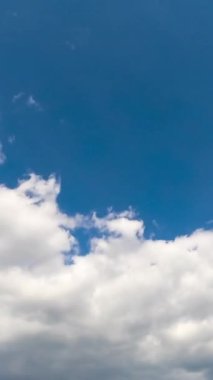 Gökyüzündeki bulutların hareketi. Mavi, parlak hava zamanı. Dikey video