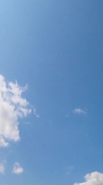 Mavi, parlak hava zamanı. Gökyüzündeki bulutların hareketi. Dikey video