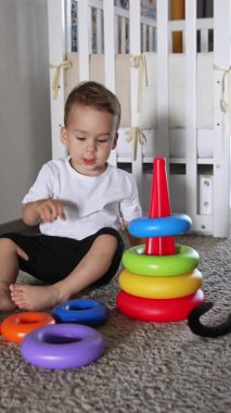 Oyuncaklarla oynayan sevimli bir çocuk. Renkli oyuncaklar, küçük çocuk aktiviteleri. Dikey video