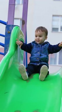 Anaokulunda dışarıda eğleniyoruz. Çocuk parkında oynayan şirin bir çocuk. Dikey video