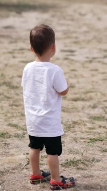 Parkta açık havada oynamak, küçük çocuk. Küçük oğlan parkta oynuyor. Dikey video