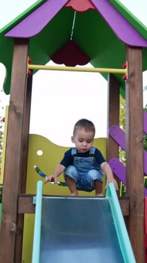Renkli oyun parkında küçük bir çocuk. Parktaki küçük neşeli çocuk. Dikey video