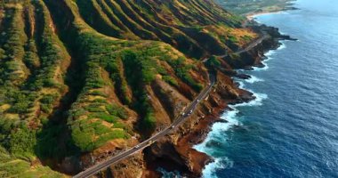 Elmas Kafa Krateri 'nin yeşil yamacından geçen arabalar. Hawaii, ABD 'nin kayalık kıyıları yakınlarındaki Pasifik Okyanusu' nun üzerinde yükseliyor..