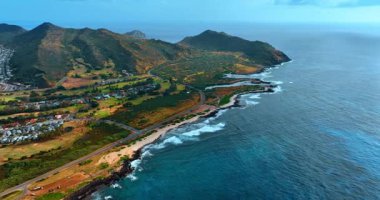 Dar kumlu sahil ve dağlarla çevrili yeşil rıhtım. Honolulu, Oahu, Hawaii, ABD manzaralı. Pasifik Okyanusu üzerindeki insansız hava aracının görüntüleri..