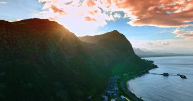 Güneş dağın arkasında batıyor. Rocky Sahili, Oahu, Hawaii, ABD gün batımında. Gökyüzünde güzel pembe bulutlar manzaranın üstünde.