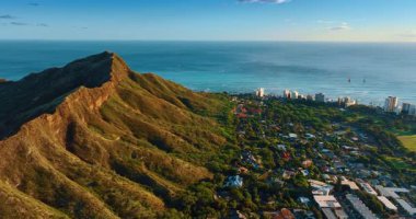 Honolulu, Hawaii, ABD 'deki Elmas Kafa Krateri' nin yeşil yamacındaki yerleşim alanının üzerinde uçuş. Pasifik Okyanusu 'nun masmavi sularında çok az yelkenli vardır..