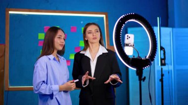 Stüdyo içeriği sağlayan genç kadınlar. İki genç kadın renkli notlarla dolu parlak bir stüdyoda kayıt yaparken yaratıcı bir tartışmaya giriştiler..