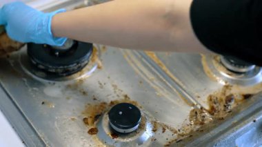 Mutfakta yağlı bir sobayı temizliyorum. Eldivenli bir insan, güneşli bir günde kirli bir sobayı temizler, yağını ve kirini temizler..