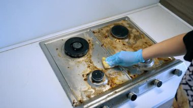 Kirli bir sobayı temizliyorum. Mavi eldiven giyen biri, gün boyunca kirli bir sobanın üstünü temizler..