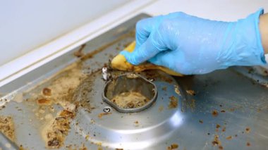 Pişirdikten sonra mutfak aletlerini temizliyorum. Mavi eldivenli bir insan yemek pişirdikten sonra mutfak malzemelerini yağ ve yemek artıklarıyla temizler..