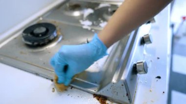 Yağlı sobayı temizliyorum. Eldiven giyen biri kirli bir sobayı süngerle temizler, yağ ve kir temizler..