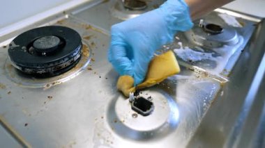 Kirli mutfak sobası yüzeyleri. Kirli soba yiyecek artıklarını ve kiri gösteriyor. Metal yüzeylerde temizlik ürünleri var..