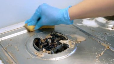 Fırını özenle ve titizlikle temizliyorum. Eldiven giyen biri kirli bir sobayı temizler. Yağ ve kiri etkili bir şekilde temizler..