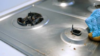 Ocaktan yağ alınıyor. Eldiven takan kişi, yemek ve yağ parçacıklarını temizlemek için sobayı siler ve temiz bir yemek yüzeyi oluşturur..