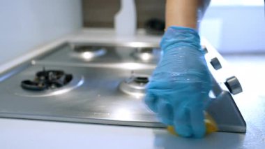 Mutfak sobasını özenle temizliyorum. Eldivenli bir el paslanmaz çelik bir mutfak sobasını süngerle siler ve pişirdikten sonra temizliği sağlar..