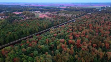 Nehrin kenarından renkli yapraklar. Sonbahar renklerini gösteren gür ağaçlar huzurlu bir nehrin çevresini sarar ve akşam ışığında doğanın güzelliğini gözler önüne serer..