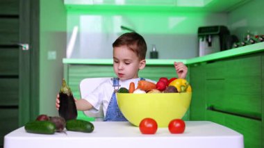 Çocuk mutfakta taze sebzelerin tadını çıkarıyor. Genç bir çocuk taze ürünlerle dolu, sağlıklı beslenmeyi teşvik eden parlak bir mutfakta sebze tutuyor..