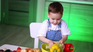 Mutfakta sebze doğrayan çocuk. Genç bir çocuk neşeli bir mutfak ortamında neşe içinde renkli sebzeleri sınıflandırıyor, eğlenceli bir yemek pişirme aktivitesine katılıyor..