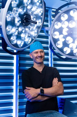 Cerrah ameliyata hazır. Gülümseyen bir cerrah, parlak bir ameliyathanede, profesyonellikle prosedüre hazır bekliyor..