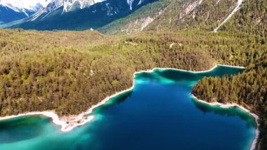 Avrupa 'daki dağlarda inanılmaz bir turkuaz göl. Kalın yeşil ormanlar resimli kayaları kaplar. Hava görünümü.