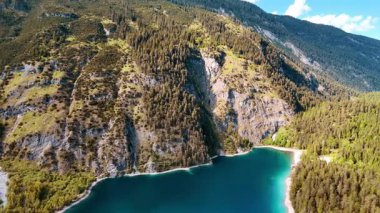 Dağlardaki turkuaz gölün üzerinde uçuyorlar. Erişilemez kayalara bak. Her yer yeşil ormanlarla kaplanmış..
