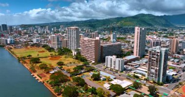 Pasifik Okyanusu 'ndaki Honolulu şehir manzarası. Arkaplanda yoğun bulutlar altında yemyeşil dağlar. Hava görünümü.