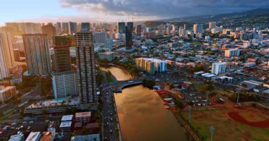 Güneşin batışı Honolulu, Hawaii, ABD manzarasını kamaştırıyor. Ala Wai Kanalı üzerindeki İHA uçuşu bulutlu gökyüzünü yansıtıyor.