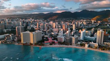 Günbatımında modern şehir manzarası Honolulu, Hawaii, ABD. Arkaplanda dağların karanlık siluetleri. Hava görünümü.
