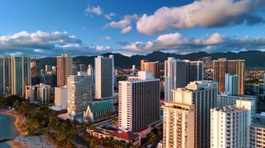 Pasifik Okyanusu kıyısındaki görkemli, lüks, yüksek binalar. Tatil yeri Waikiki, Honolulu, Hawaii, ABD gün batımında. Dağ siluetleri arka planda. Üst görünüm.