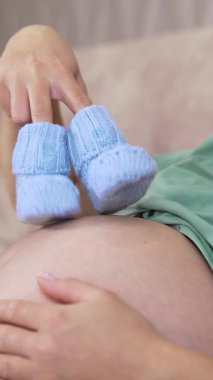 Evde hamile bir kadın var. Hamile bir kadın hamile karnında bebeği tutuyor.