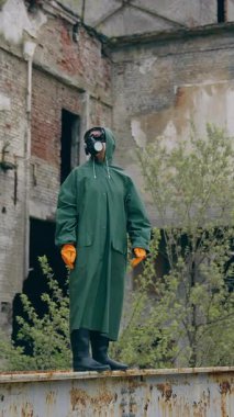 Harabelerde koruyucu maskeli bir adam. Gaz maskesi takan bir adamın dramatik portresi yıkılmış binanın hemen yanında.