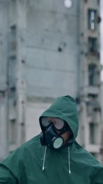 Atomik kazazede, kıyamet sonrası ortamında. Terk edilmiş binanın arka planında gaz maskeli bir adamın portresi.