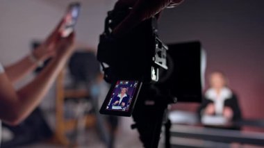 Erkek el, kadın muhabiri gösteren bir kameraya dokunur. Kapatın. Tanımlanamayan kişi bulanık arkaplanda akıllı telefondan video çekiyor.