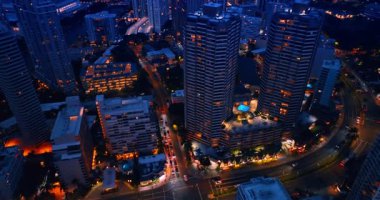 Modern, hareketli şehirde alacakaranlık vakti. İnsansız hava aracı Waikiki, Honolulu, Hawaii 'de şehir ışıklarıyla gün batımından sonra uçuyor. Üst görünüm.