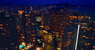 Modern bir şehrin şehir manzarası boyunca aydınlatılmış bir yol. Yukarıdan bakınca, Waikiki 'nin gece neşesi yerine geliyor..