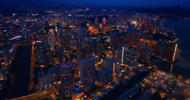 Waikiki 'nin gece vakti şehir ışıklarıyla dolu göz kamaştırıcı manzarası. İHA görüntüleri yat kulübünün üstündeki rıhtıma yaklaşıyor..