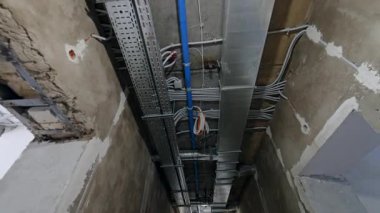 Uzun koridorun tavanında metal ve plastik borulardan oluşan karmaşık bir sistem. Eski bina yenileme konsepti. Düşük açı görünümü.