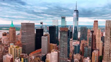 New York şehir merkezinin çarpıcı manzarası. Doğu Nehri kıyısındaki gökdelenlere yaklaşıyoruz. Arkaplanda gri bulutlu gökyüzü.