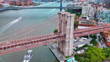 İnsanlar yürüyor ve arabalar East River üzerindeki Brooklyn Köprüsü 'nden geçiyor. Sürat tekneleri su yüzeyinde hareket ediyor. New York, ABD 'de hava görüntüsü.