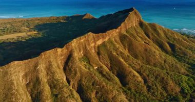 Parlak batan güneşin ışığında Elmas Kafa Krateri 'nin keskin kenarı. Volkanik bir kayanın engebeli yamaçlarında uçmak. Oahu, Hawaii, ABD.